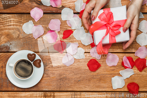 Image of Valentines Day gift and Female hands on wooden background 