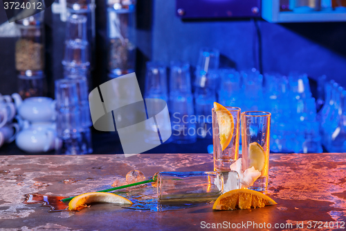 Image of The spilled cocktails with ice cubes on blue color in the bar