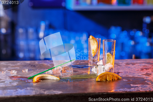 Image of The spilled cocktails with ice cubes on blue color in the bar