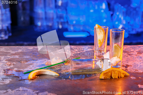 Image of The spilled cocktails with ice cubes on blue color in the bar