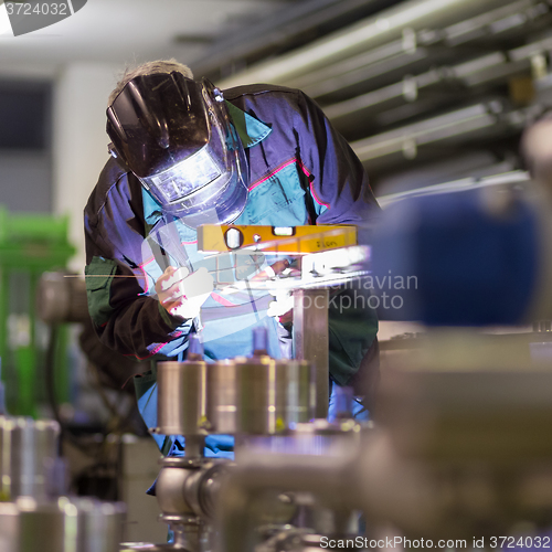 Image of Industrial worker welding in metal factory.