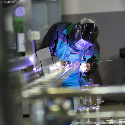 Image of Industrial worker welding in metal factory.