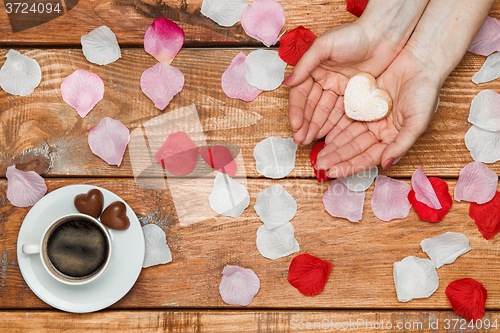 Image of Valentines Day concept.  Female hands with  hearts on wooden background 