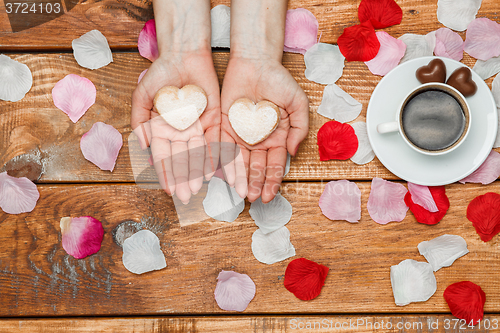 Image of Valentines Day concept.  Female hands with  hearts on wooden background 