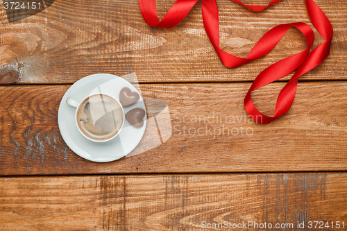 Image of The red  ribbon on  wooden background with a cup of coffee