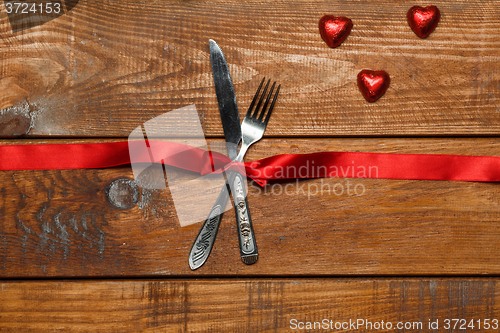 Image of The red ribbon, fork and knife on wooden background