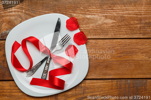 Image of The red ribbon in plate on wooden background