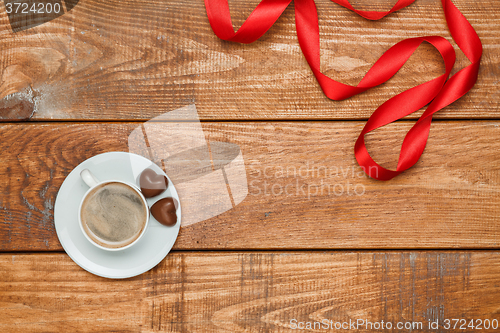 Image of The red  ribbon on  wooden background with a cup of coffee