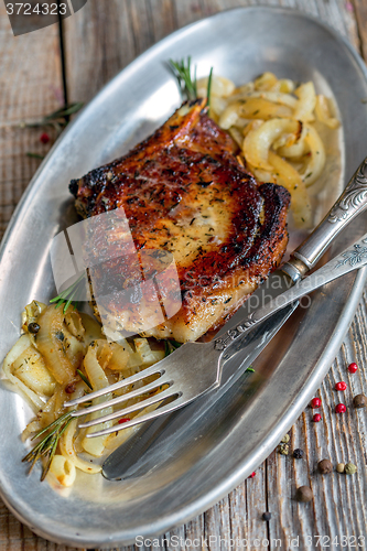 Image of Pork chop with rosemary and fried onions.