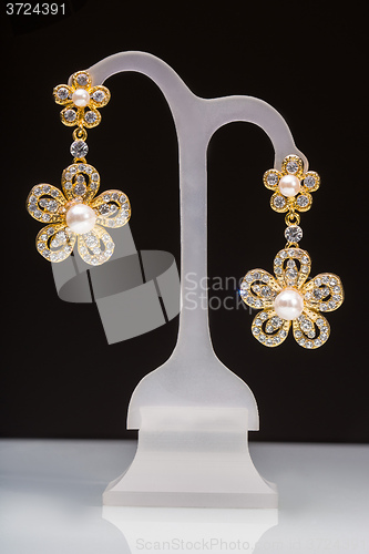 Image of gold earrings with white little stones. in the form of flowers