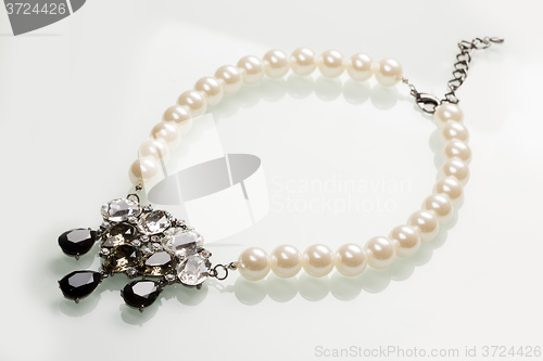 Image of pearl necklace with black stones on a white 