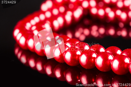 Image of necklace of red pearls on black background