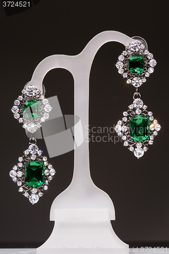 Image of earrings with green stones on a stand