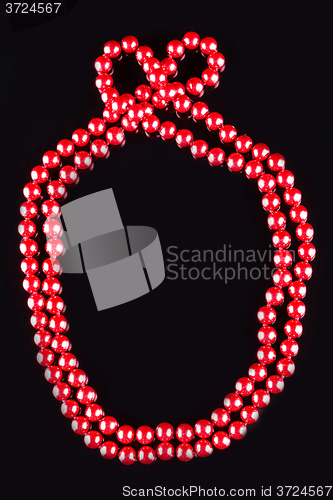 Image of necklace of red pearls on black background
