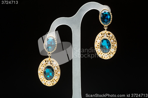 Image of earrings with blue stones on the black 