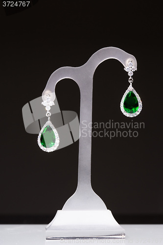 Image of earrings with green stones on a stand