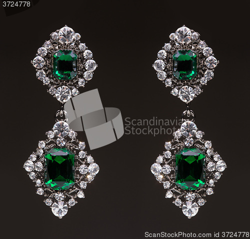 Image of earrings with green stones on the black 