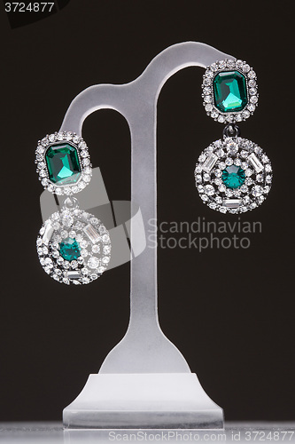 Image of earrings with green stones on a stand