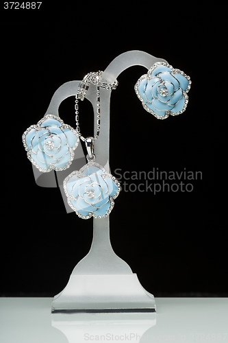 Image of earrings with blue stones on the black. flowers