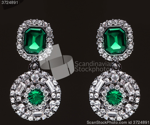 Image of earrings with green stones on the black 