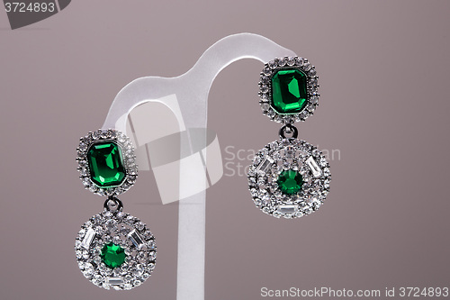 Image of earrings with green stones on the gray