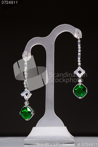 Image of earrings with green stones on a stand