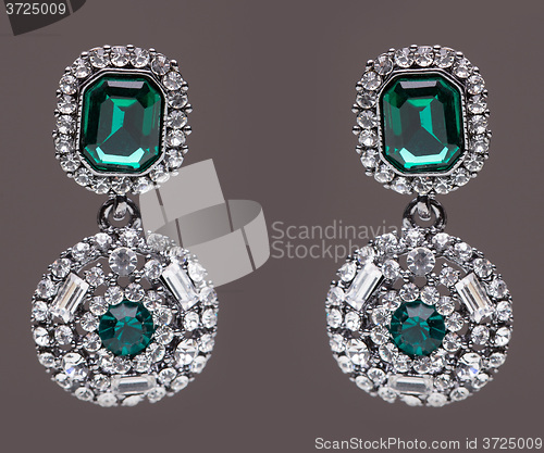 Image of earrings with green stones on the gray