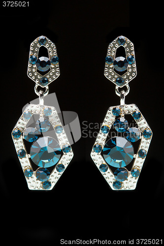 Image of earrings with blue stones on the black 