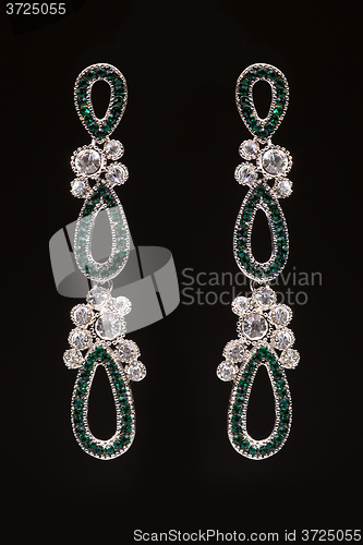 Image of earrings with green stones on the black 