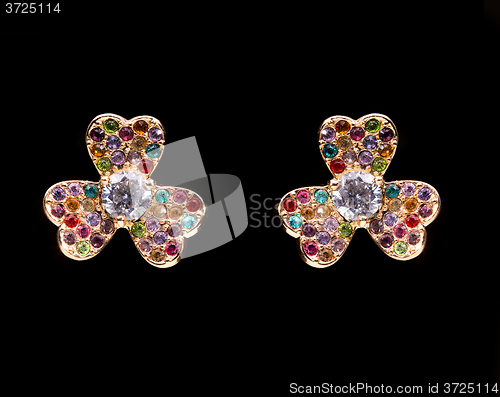 Image of gold earrings with white little stones. in the form of flowers