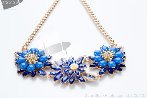 Image of plastic necklace. three blue flower