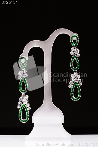 Image of earrings with green stones on a stand