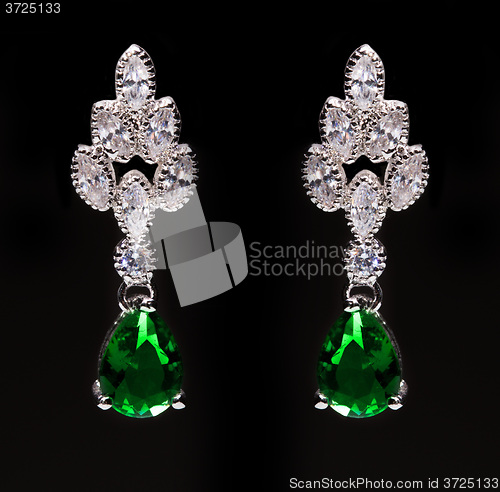 Image of earrings with green stones on the black 