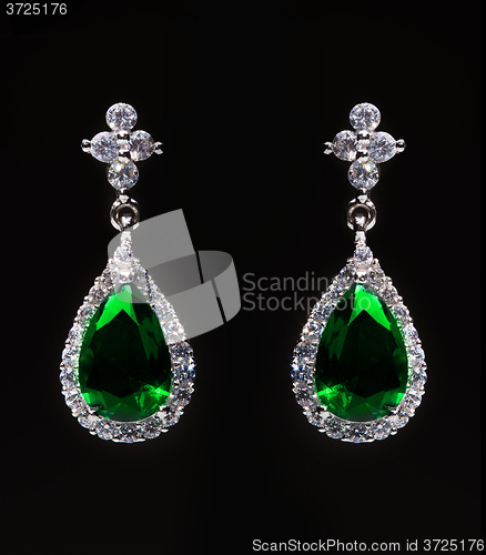 Image of earrings with green stones on the black 