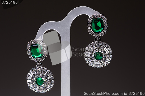 Image of earrings with green stones on the black 