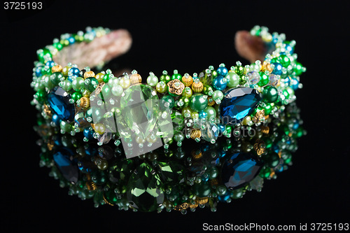 Image of diadem with large green stones. bijouterie. on black background