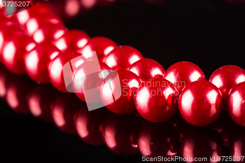 Image of necklace of red pearls on black background