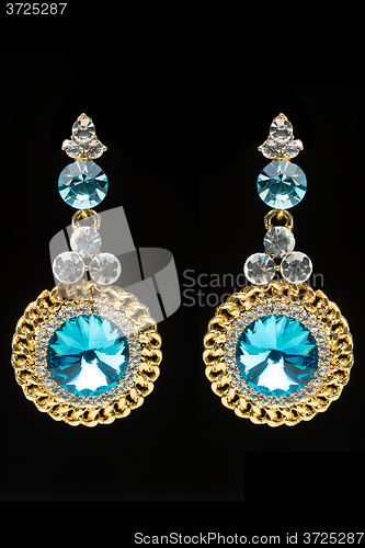 Image of earrings with blue stones on the black 