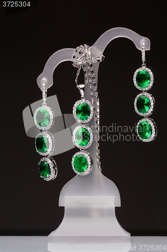 Image of earrings with green stones on a stand