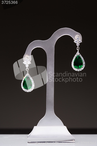 Image of earrings with green stones on a stand