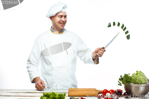 Image of Chef cutting a green cucumber in his kitchen