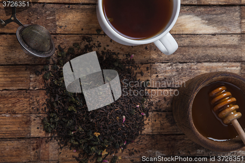 Image of The cup of tea and honey on a wooden table