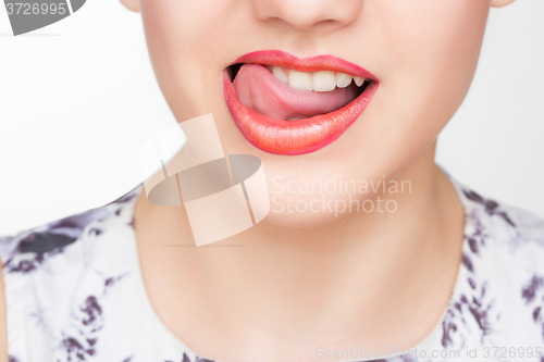 Image of Licking lips. Close-up of young woman licking lips