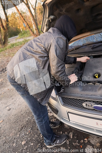 Image of Hooligan breaking into car