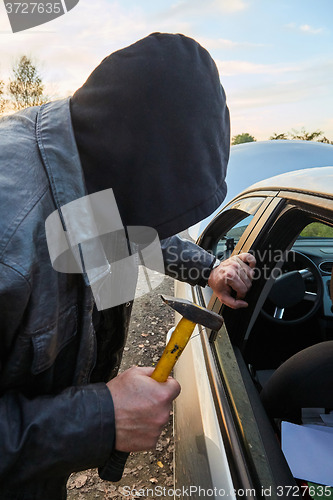 Image of Hooligan breaking into car