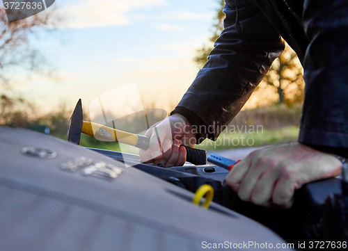 Image of Hooligan breaking into car