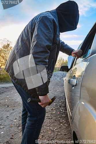 Image of Hooligan breaking into car