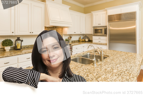 Image of Hispanic Woman Leaning Against White In Custom Kitchen Interior