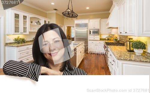 Image of Hispanic Woman Leaning Against White In Custom Kitchen Interior