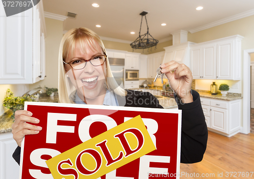 Image of Young Woman Holding Sold Sign and Keys Inside New Kitchen